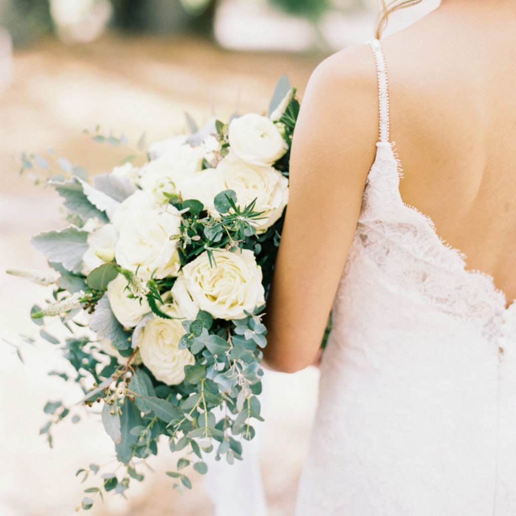 Classic style wedding inspiration, close up of a bride holding a wedding bouquet of white roses and greenery