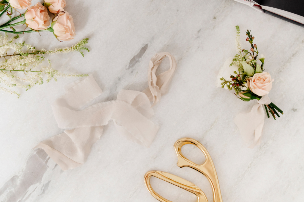 How to budget for a styled shoot? 
Romantic wedding styling accessories: blush ribbon, golden scissors, and boutonnière with a blush rose and greenery.